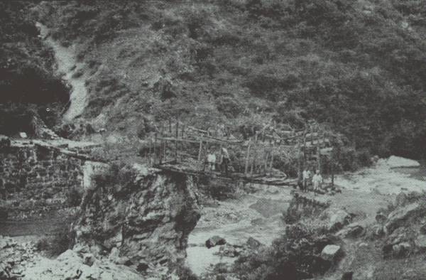 FAR IN THE WILDS OF UNSURVEYED Y&Uuml;N-NAN

Picture gives only a scant idea of the difficulties of negotiating
country of this nature. When river is high, there is no bridge. Author
on bridge.