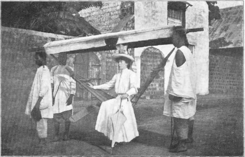 Mrs. Davis in a Borrowed "Hammock," the Local Means
of Transport on the West Coast.