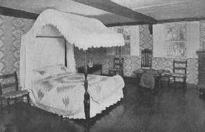 A pleasing design of the old field bed. The chairs here
are samples of some eighteenth century manufacture that are to-day
reproduced in admirable consistency. The patch work quilt is interesting
and the bed hanging are exceptionally good.