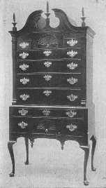 The general proportions, the broken pediment and torch or
flame ornaments and drops, large brasses, and cabriole legs all show
that this splendid example of a highboy belongs to the same time as the
desk, about 1750.