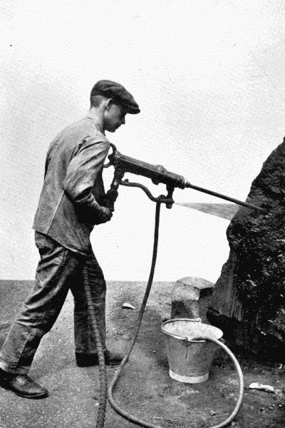 By permission of The Mining Engineering Co., Ltd., Sheffield
Pneumatic Hammer Drill
This tool is used by miners for making holes in hard rock, preliminary to
blasting. Note the spray of water, which prevents the stone dust rising and
getting into the miner's lungs.&mdash;See p. 220