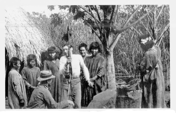 Fig. 22&mdash;Trading with Machiganga Indians in a reed swamp
at Santao Anato, Urubamba Valley, before Rosalina. Just outside the
picture on the right is a platform on which corn is stored for
protection against rodents and mildew. On the left is the corner of a
grass-thatched cane hut.