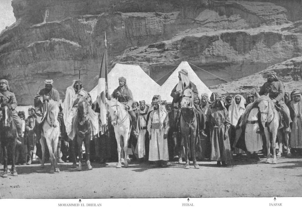 Photo wide shot of men standing and on horses facing
                forward; Mohammed el Dheilan, Feisal, and Jaafar
                indicated