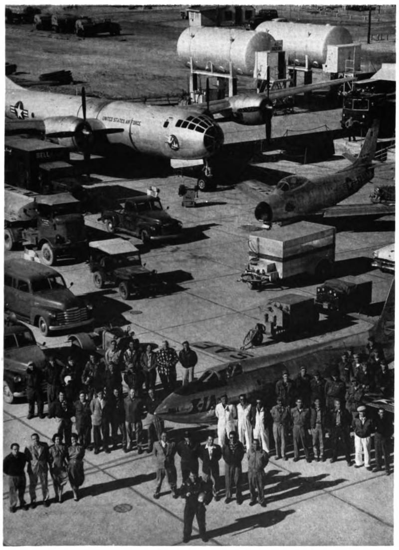 A large crew with various vehicles and an airplane in the background