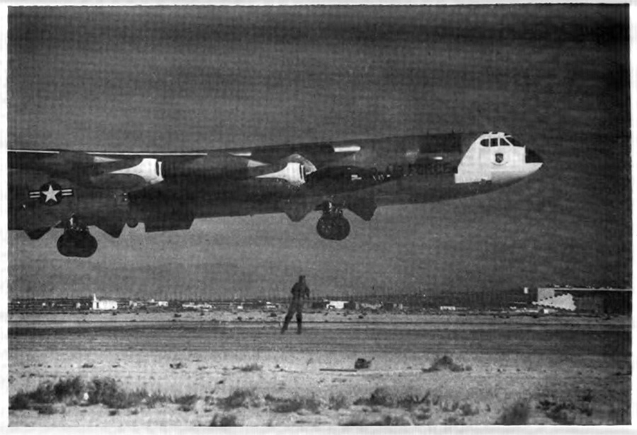 A plane taking off with a man standing looking up at it